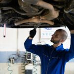 man bij een autogarage voert een APk keuring uit