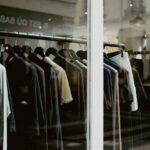 Een kledingrek met kleding die voor een raam van een kledingwinkel staat